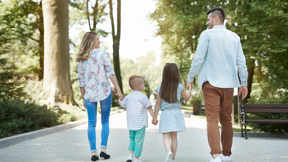 子供を真ん中に仲良く手を繋ぐ4人家族