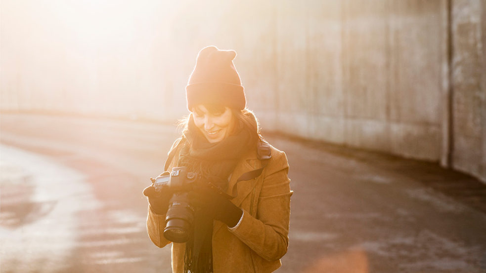 笑顔で一眼レフカメラの画面を見る女性