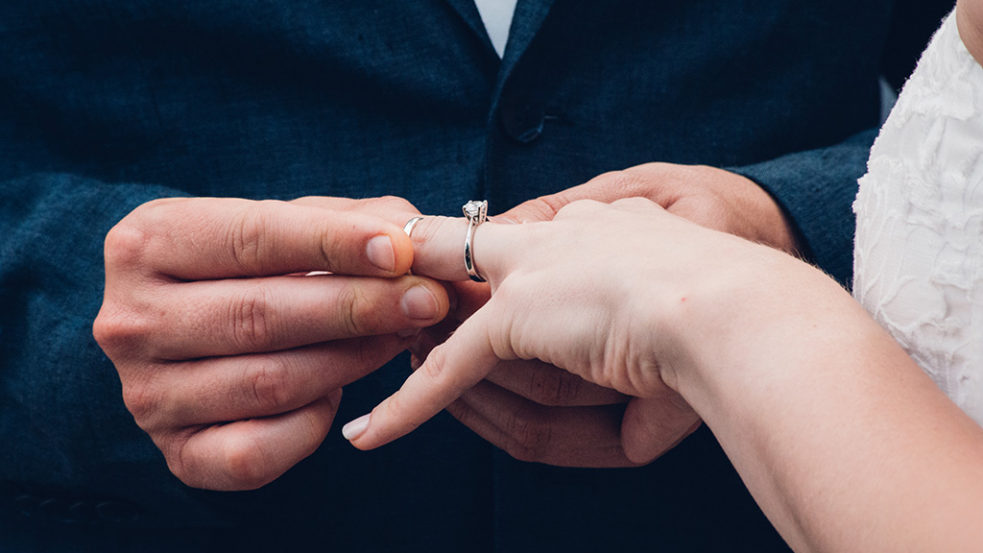 女性に結婚指輪をはめる男性の手